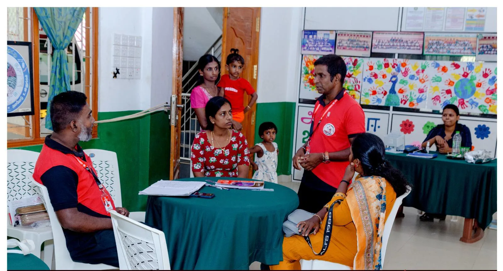 Volunteers in red shirts registering a family, including two young children, at a blood donation camp.