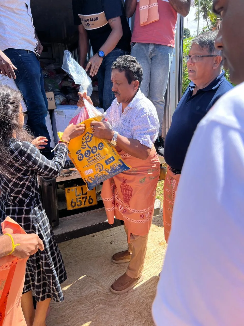 A volunteer handing a 5kg bag of rice directly to a resident beside the relief truck.