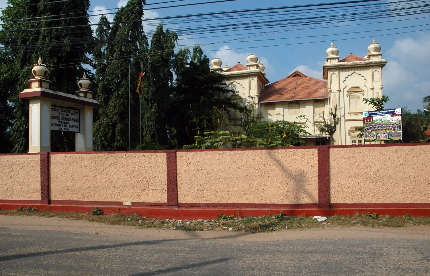 The gated entrance and heritage building of the University of Jaffna, framed by trees.